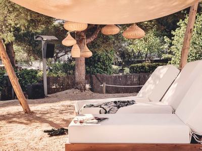 Zwei weiße Liegen unter einem Sonnensegel mit Naturblick und warmem Tageslicht.