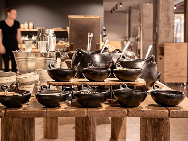 Schwarze Keramikschalen und Töpfe in verschiedenen Größen auf Holztisch, Verkaufsraum im Hintergrund.