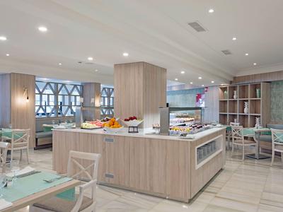 Lichte ontbijtruimte met buffet-eiland, modern houten meubilair en gedekte tafels.