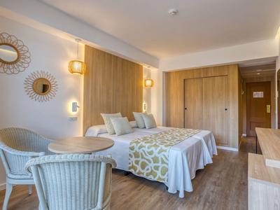 Knusse hotelkamer met twee eenpersoonsbedden, stoelen, tafel en warme houten accenten.