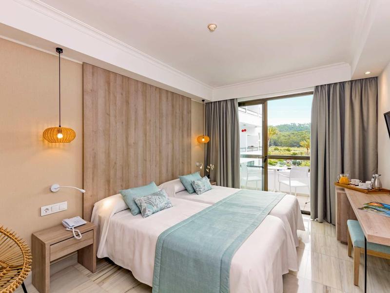 Camera d'hotel moderna con due letti, parete di legno, grande finestra e vista sul paesaggio.