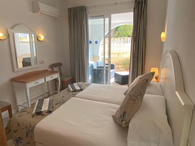Hell eingerichtetes Hotelzimmer mit zwei Betten, Schreibtisch und einem Balkon mit Aussicht.