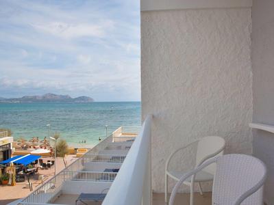 Balkon mit weißen Stühlen und Meerblick an einem bewölkten Tag.