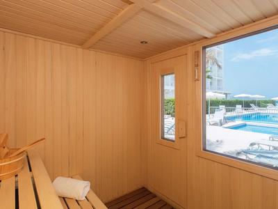 Sauna mit Holzwänden, Blick auf Pool und Liegestühle im Freien.