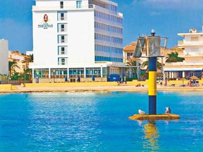 Modernes Hotelgebäude am Strand mit blauem Meer und klarem Himmel im Vordergrund.