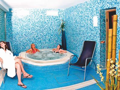 Entspannungsbereich mit Whirlpool, Stühlen und Mauer mit blauen Mosaikfliesen.