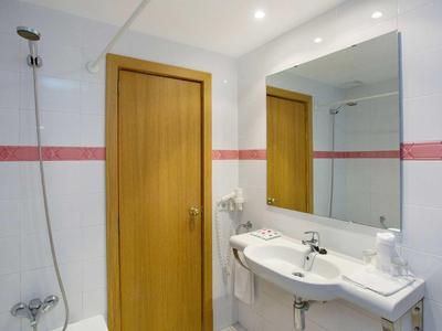 Helles Badezimmer mit großer Spiegel, Waschbecken und Holztür.