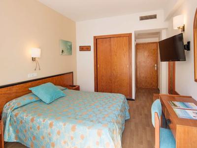 Ein Hotelzimmer mit Doppelbett, Schreibtisch, Stuhl, Fernseher und Kleiderschrank.