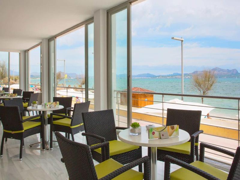 Café moderne avec vue sur le lac et les montagnes, intérieur lumineux avec grandes fenêtres.