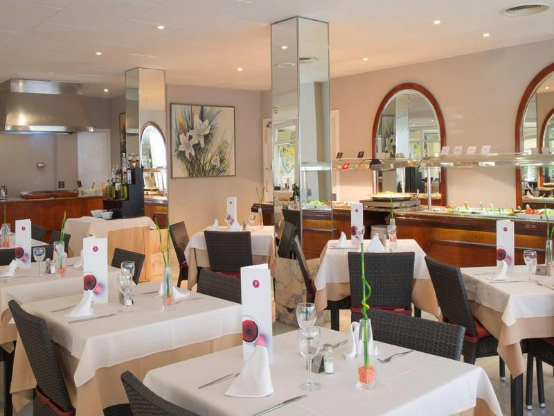 Salle de restaurant élégante avec nappes blanches, mobilier moderne et lumière chaleureuse.
