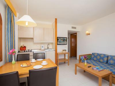 Salon avec coin repas, canapé, meubles en bois et appareils de cuisine dans une ambiance claire.