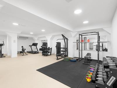 Heller Fitnessraum mit verschiedenen Trainingsgeräten, Hanteln und Kettlebells in einem Hotel.