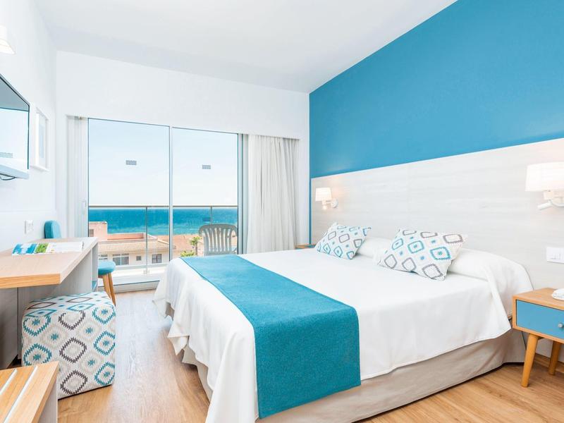 Modernes Hotelzimmer mit Meerblick, Doppelbett und blau-weißer Einrichtung