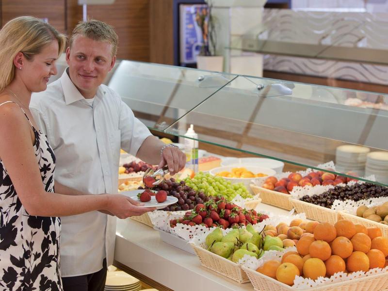 Gäste wählen frisches Obst an einem Buffet in einem Hotelrestaurant aus.