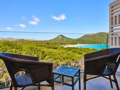 Balkon mit zwei Stühlen und Tisch mit Blick auf grüne Hügel und blauen See unter klarem Himmel
