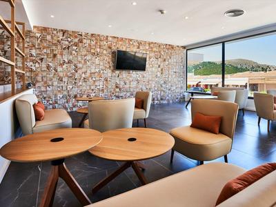 Elegant hotel lounge area with stone wall, cozy chairs, and views of pool and mountains.