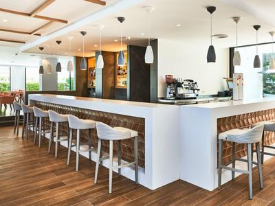 Modern hotel bar area with white chairs and wooden floor