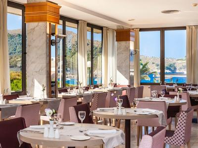 Elegant restaurant with round tables and panoramic sea and greenery views.
