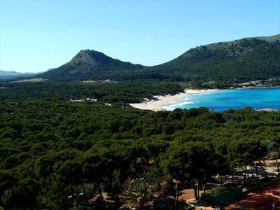 Landschaft mit Wald, Bergen und blauem Wasser unter klarem Himmel.