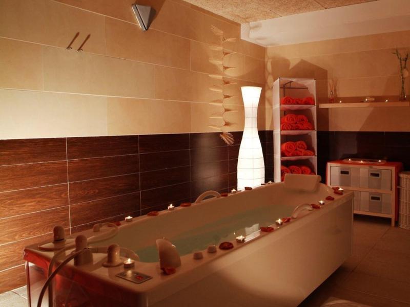 Cozy spa bathroom with illuminated tub, candles, and modern wooden walls.