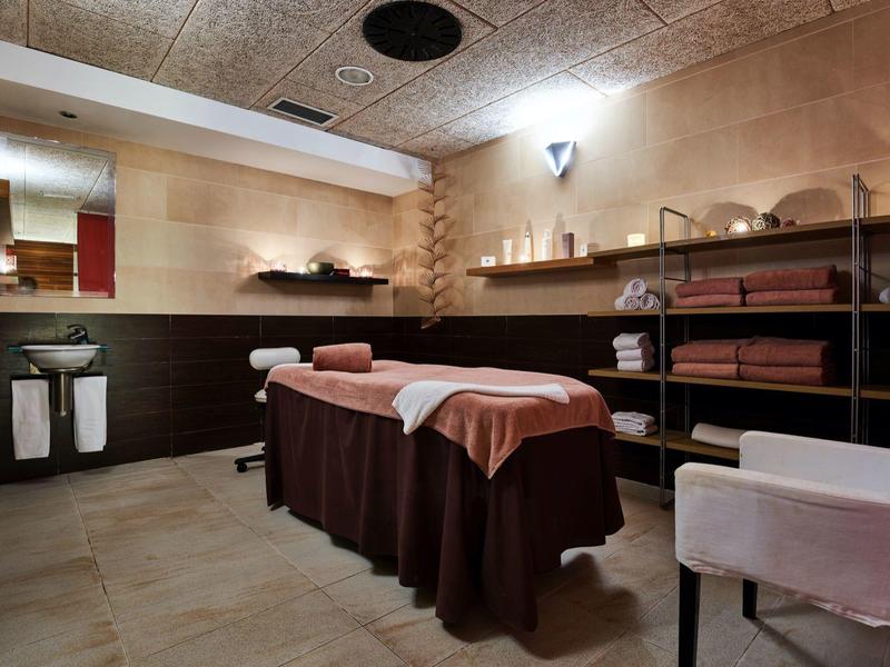 Cozy massage room with treatment table, towels, and relaxed lighting.