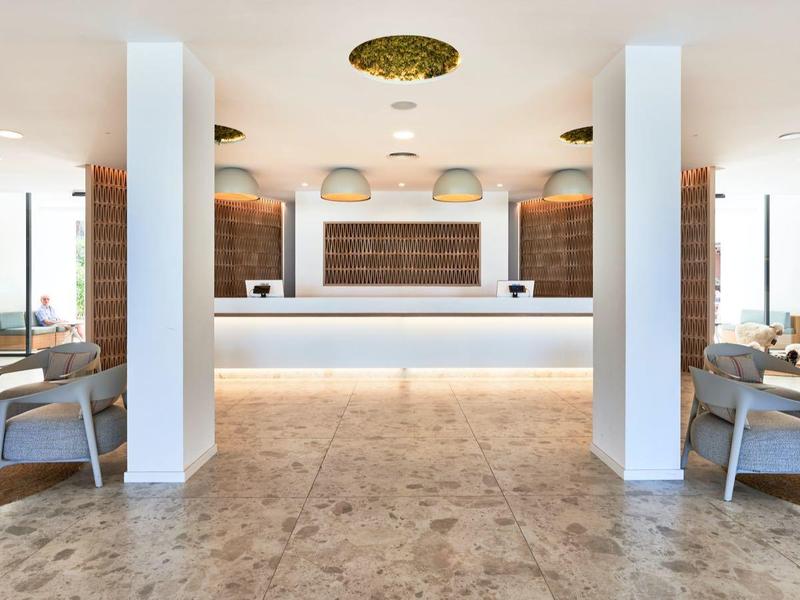 Modern hotel lounge area with tables, chairs, and bright flooring.