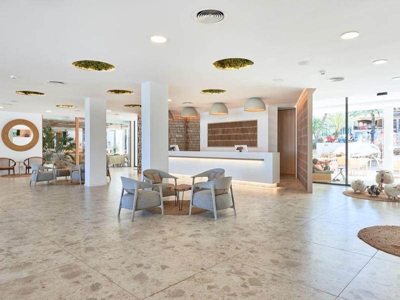 Bright hotel lobby with reception desk, seating area, and large windows.
