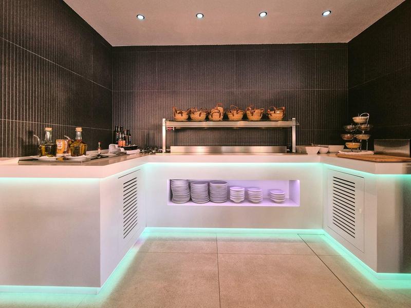 Buffet moderne avec comptoir éclairé et divers plats et vaisselle.