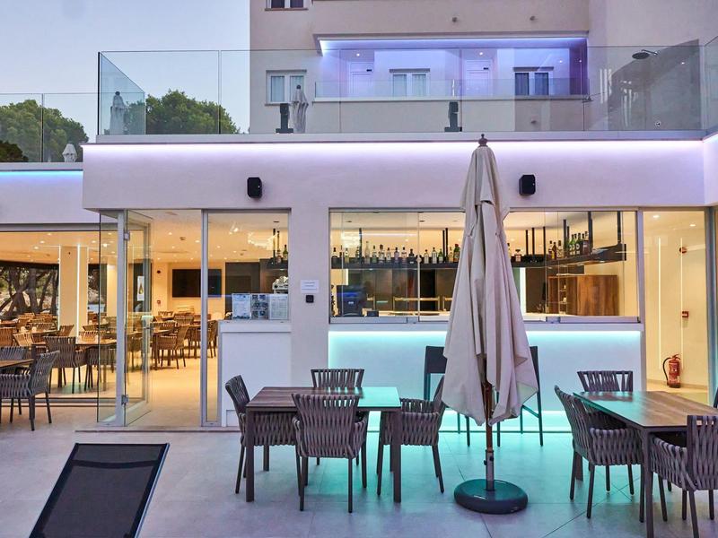 Espace extérieur moderne d'hôtel avec piscine éclairée et sièges sous parasols.