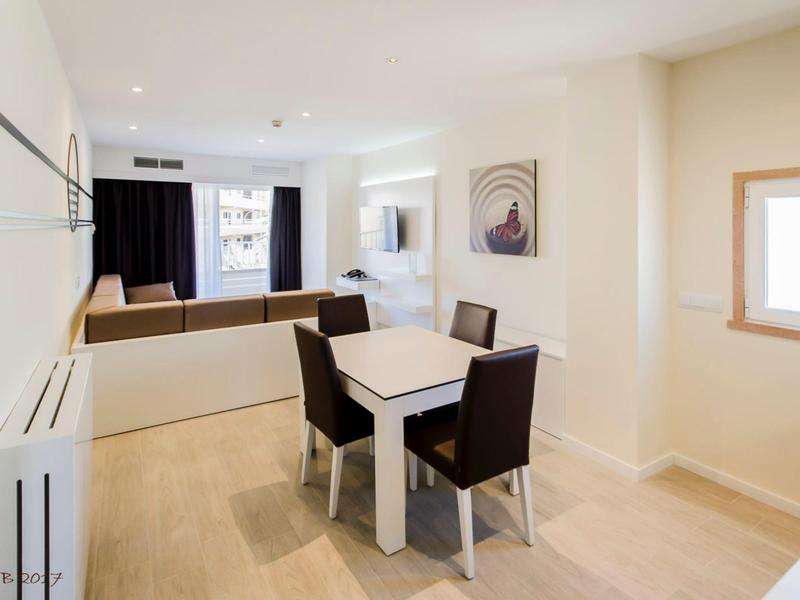 Espace de vie et repas lumineux avec table, quatre chaises et coin canapé confortable.