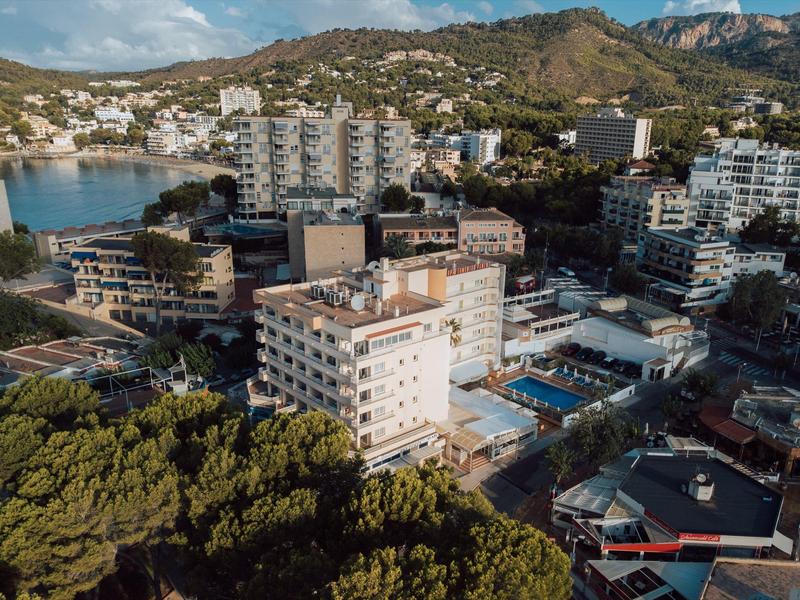 Vue aérienne d'un hôtel avec piscine dans une ville côtière montagneuse en plein jour