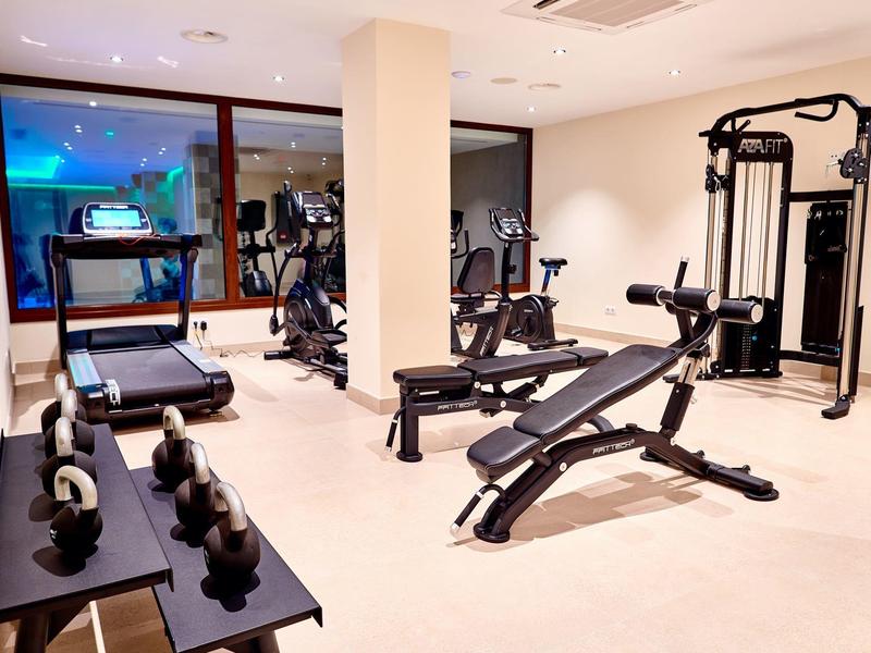 Salle de sport moderne avec divers équipements d'exercice et haltères dans un intérieur lumineux.