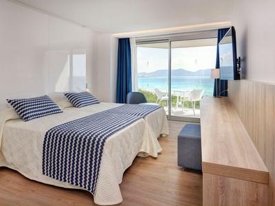 Modernes Hotelzimmer mit Doppelbett, Fenster mit Meerblick und heller Holzmöblierung.