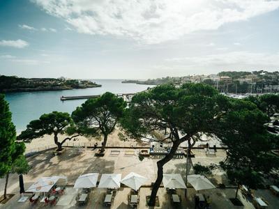 Widok na zatokę z plażą, drzewami i parasolami w pochmurny dzień.