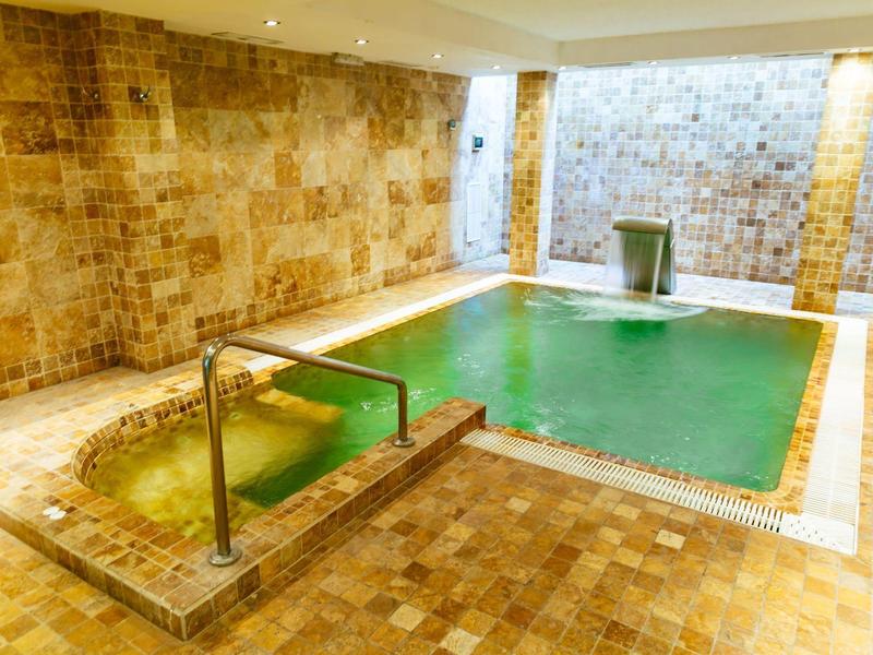Indoor pool with warm lighting and stone tile walls, perfect for relaxing in a hotel.