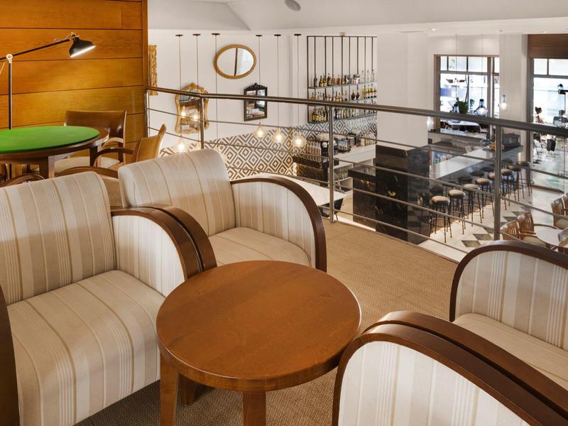 Cozy hotel lobby with striped armchairs, wooden tables, and a view of the dining area.