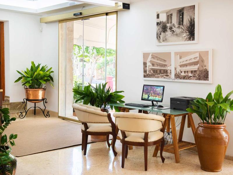 Licht, uitnodigend hotelkamer met glazen wand, houten meubels en veel groene planten.