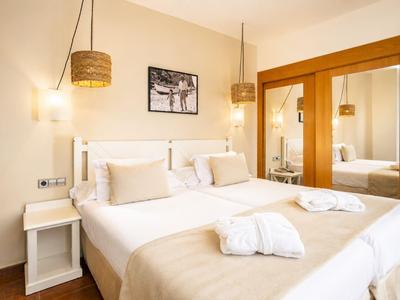 Hell eingerichtetes Hotelzimmer mit Doppelbett und großen Spiegeln.