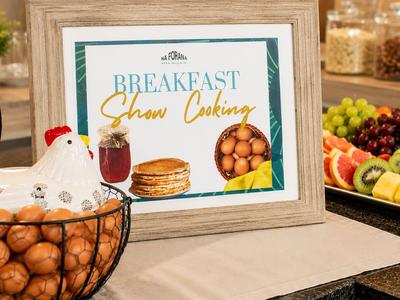 Ein Frühstücksbuffet mit Obst, Gebäck und einem Schild für Show Cooking.