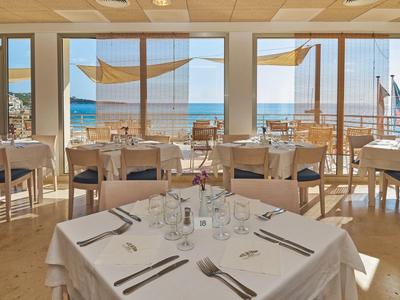 Heller Restaurantbereich mit Meerblick, gedeckten Tischen und Holzstühlen