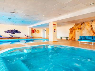 Innenraum mit Schwimmbad, Whirlpool, Liegestühlen und Felsenwand in einem Hotel