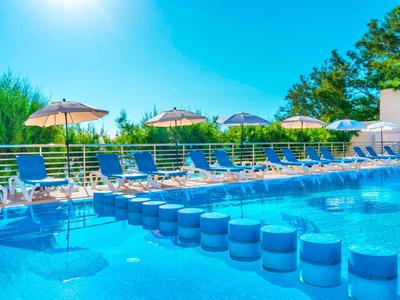 Großer Außenpool mit Sonnenschirmen und Liegestühlen an einem sonnigen Tag