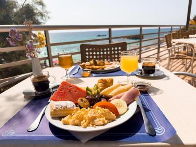 Teller mit Frühstück auf einem Tisch mit Meerblick auf einer Hotelterrasse