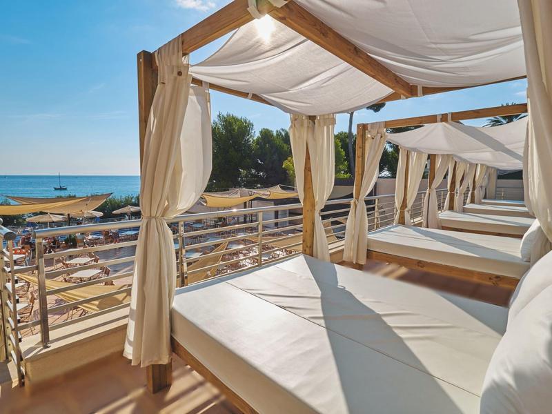 Luxuriöse Sonnenterrasse mit weißen gepolsterten Betten und Blick auf das Meer