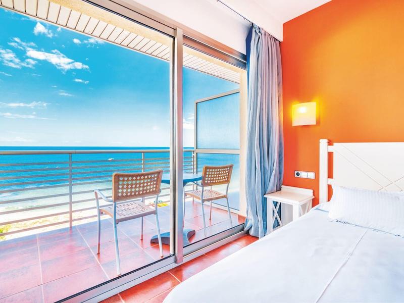 Helles Hotelzimmer mit Meerblick, Balkon und moderner Einrichtung.