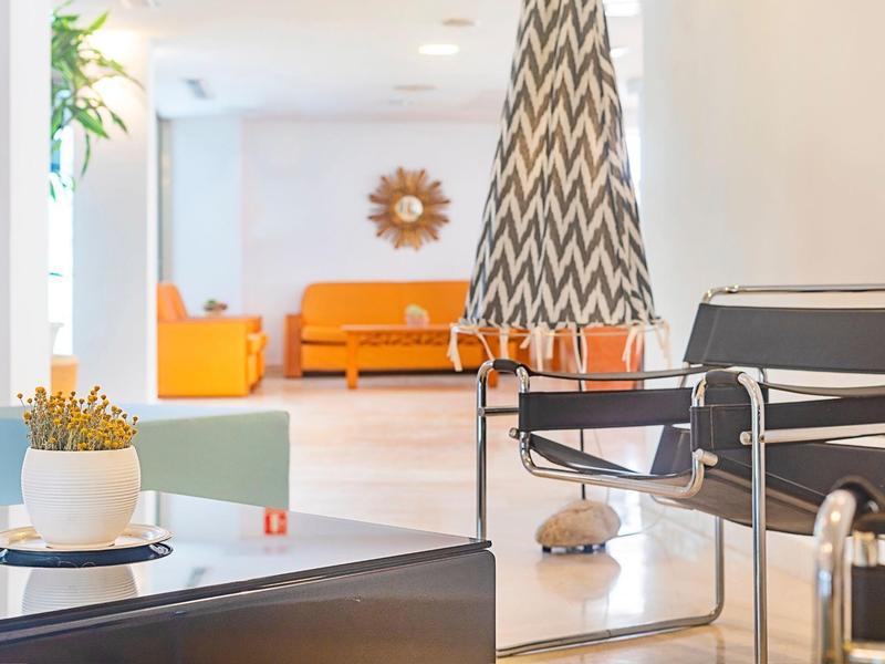 Moderner Warteraum mit schwarzen Stühlen und schachbrettmusterigem Sonnenschirm.