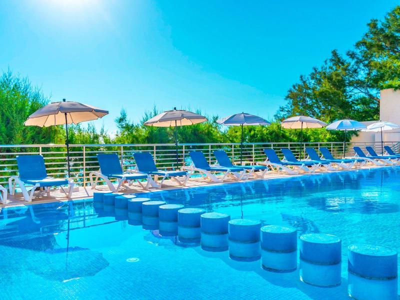 Großer Außenpool mit Sonnenschirmen und Liegestühlen an einem sonnigen Tag