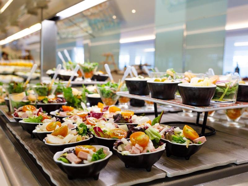 Buffet with small bowls filled with fresh salads and vegetables, ready to serve.