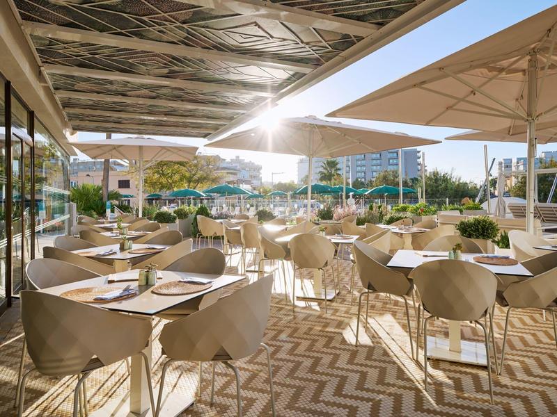 Terraza exterior soleada con mesas y sillas en un restaurante de hotel.