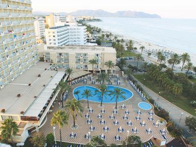 Widok na basen hotelowy z leżakami i palmami przy morzu i plaży.